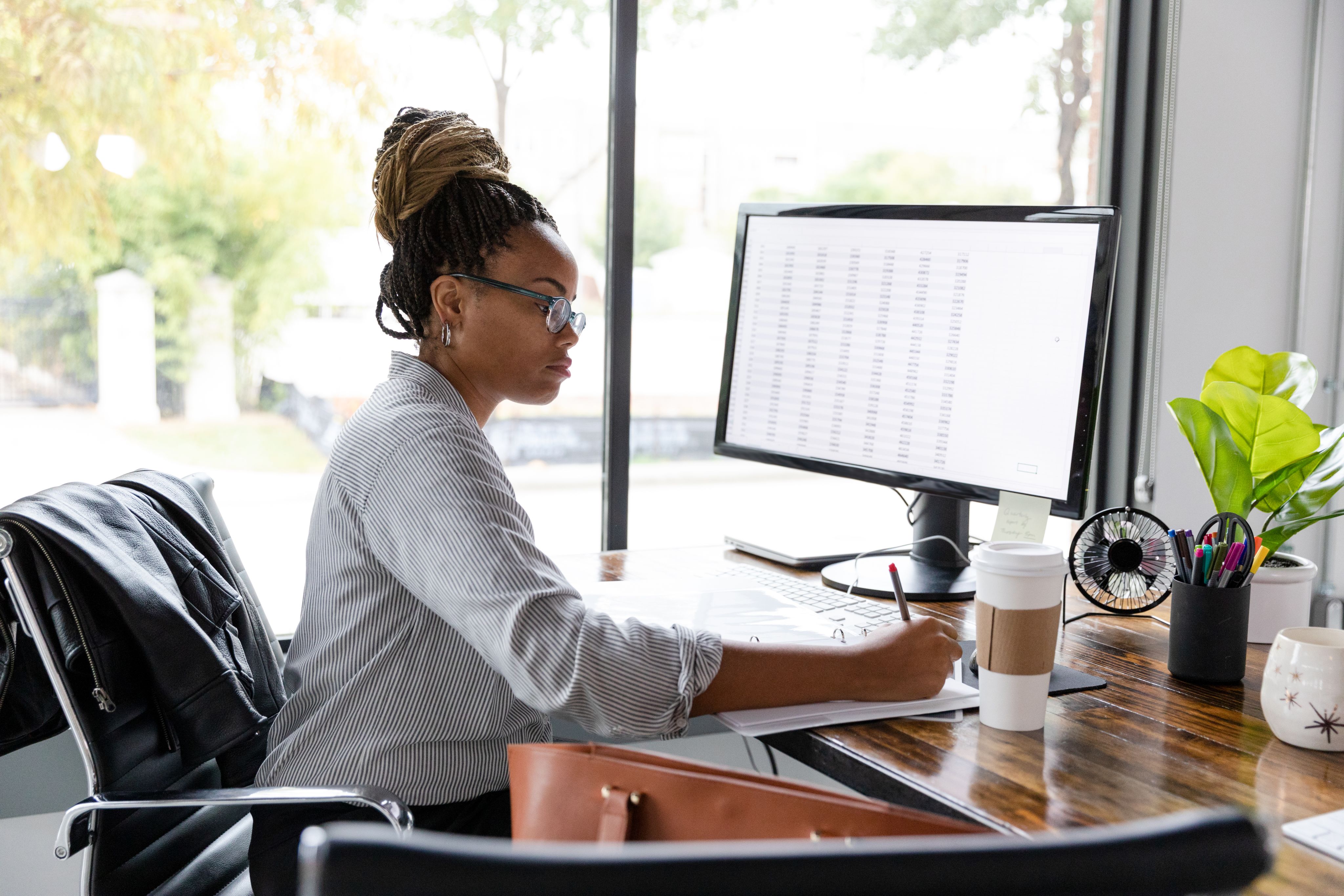 A woman sat in front of a computer screen with data figures on it