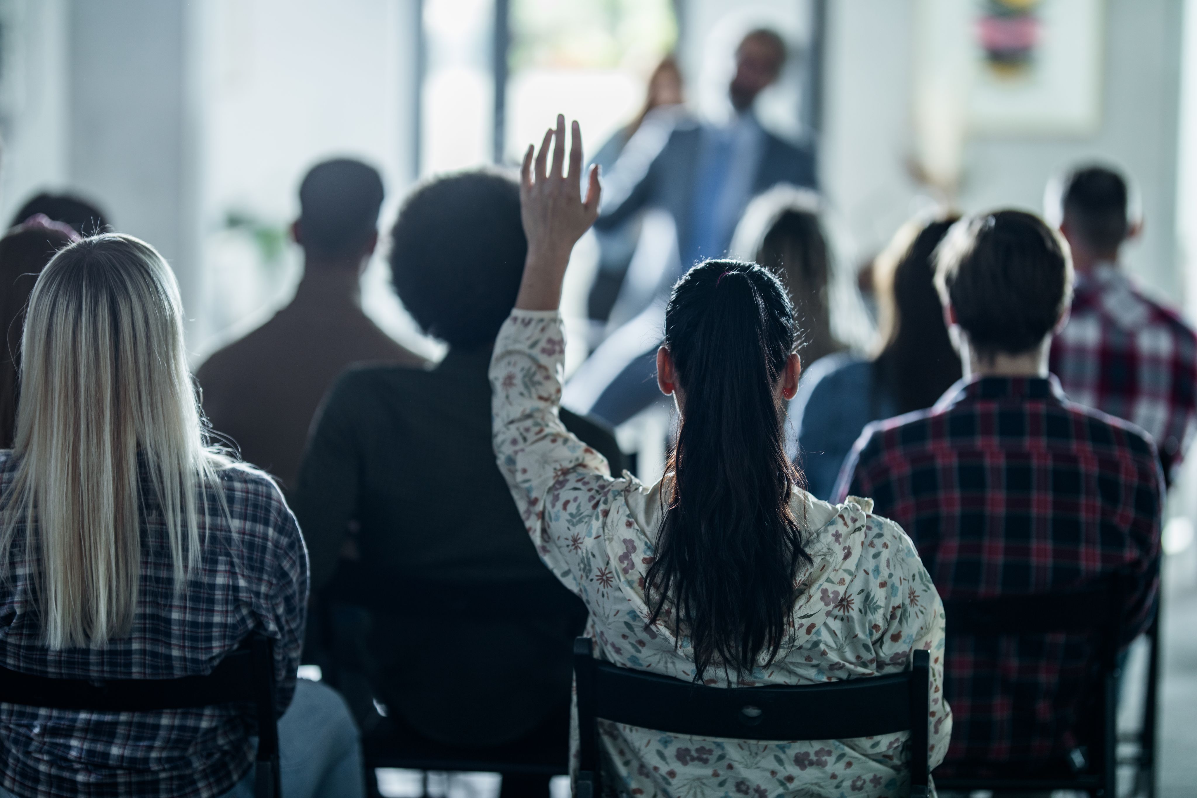 A woman raising her hand in an audience