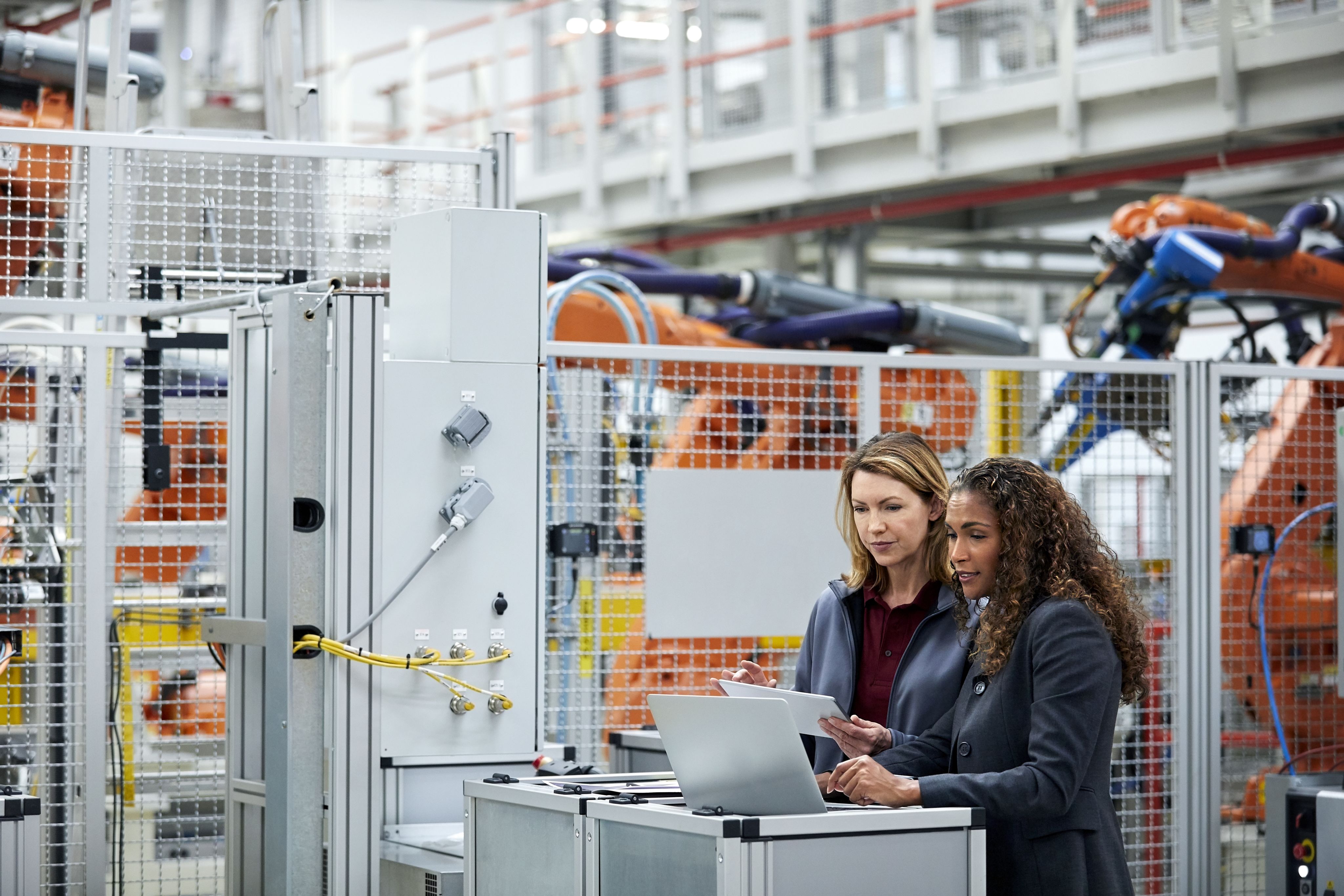 Two engineers looking at a computer screen surrounded by large machines